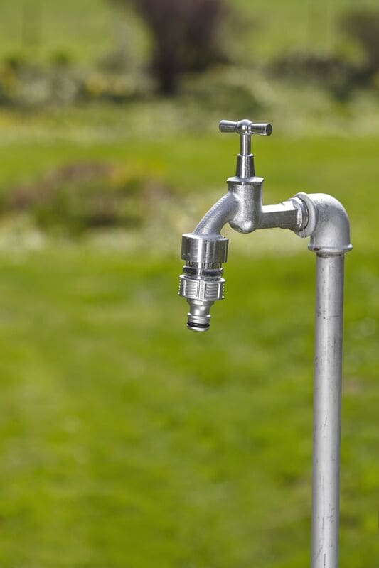 Gardena Premium Hahnverbinder_Anwendungsbild am Wasserhahn auf grüner Wiese